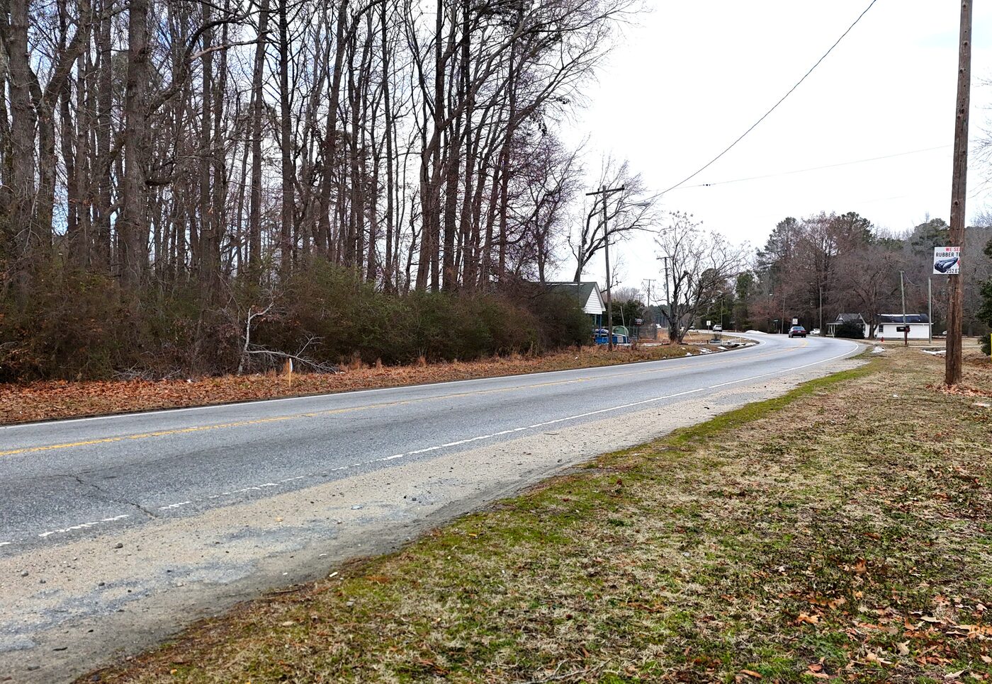 Ground-level view along Hathaway Street, a paved two-lane road, with the wooded frontage on the left and utility poles along the corridor.