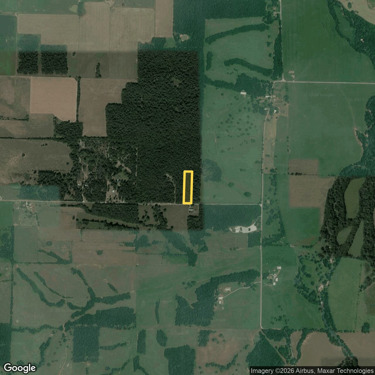 Wider aerial showing the parcel on the southeast corner of a large continuous timber block, with farmland to the east and south.