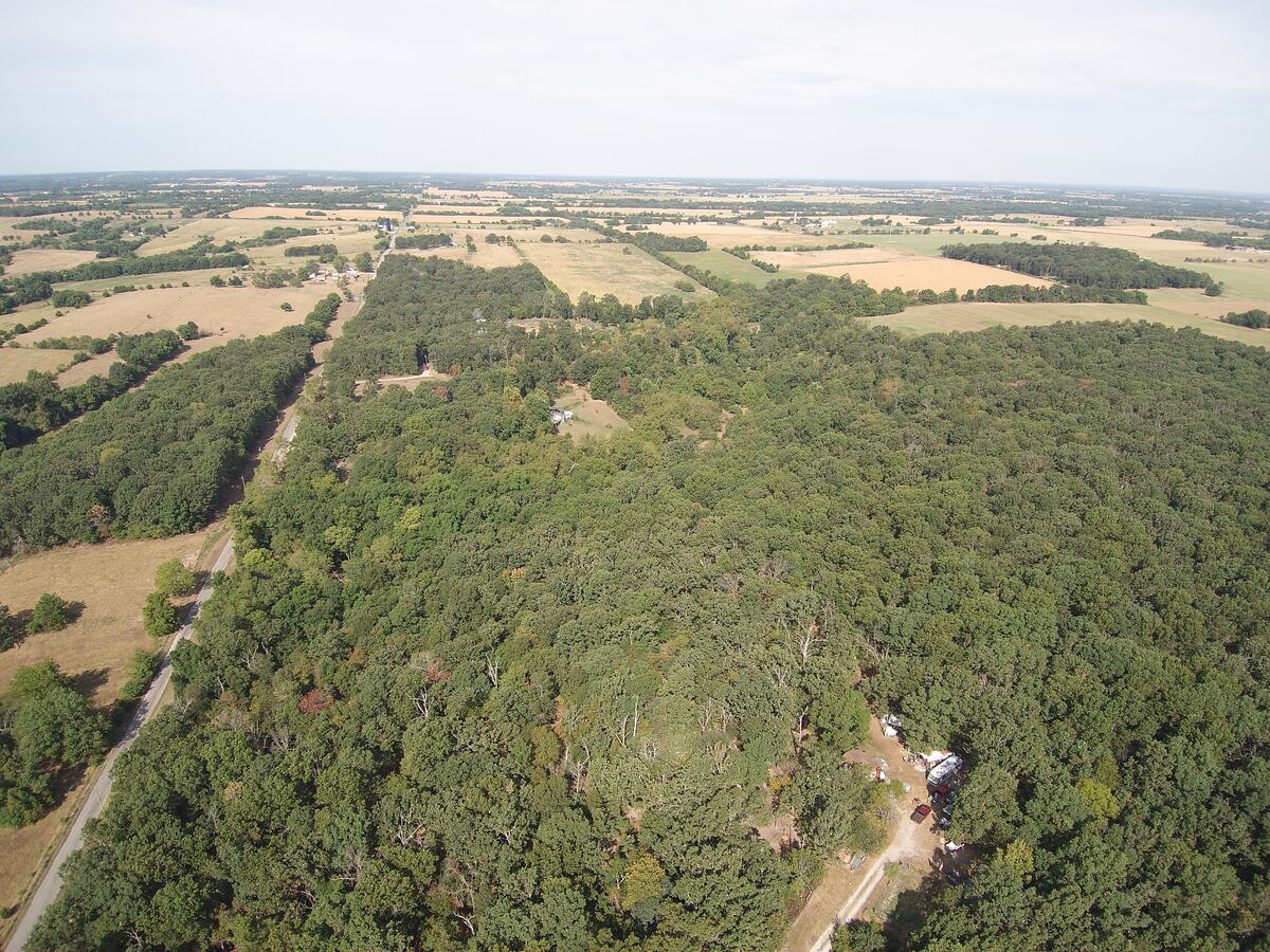 Aerial view of the county road cutting between timber and open farmland.