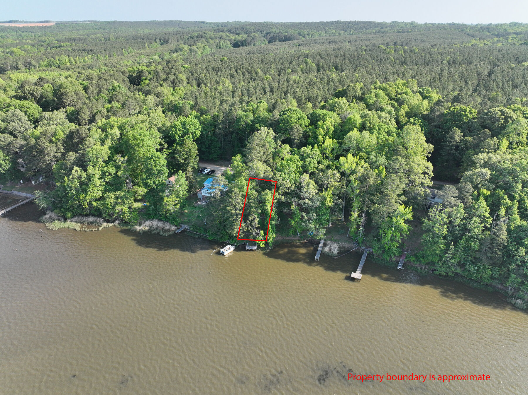 Drone view of the lake shore with the small lot outlined in red and the dock below it.